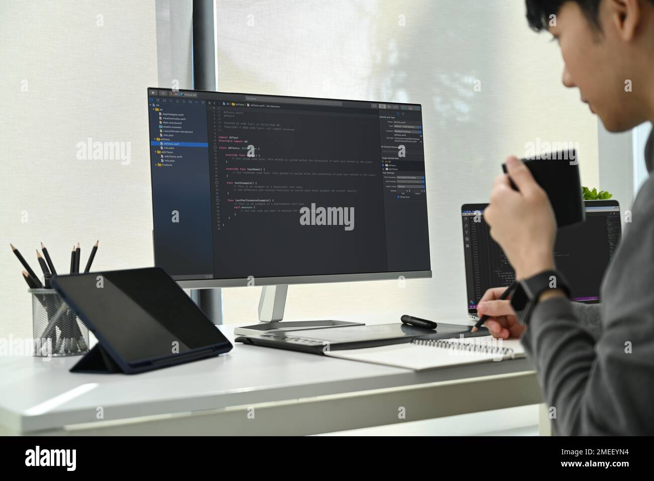 Immagine ritagliata di sviluppatori di software maschi che lavorano con dati codificati sullo schermo del computer in un ufficio moderno Foto Stock
