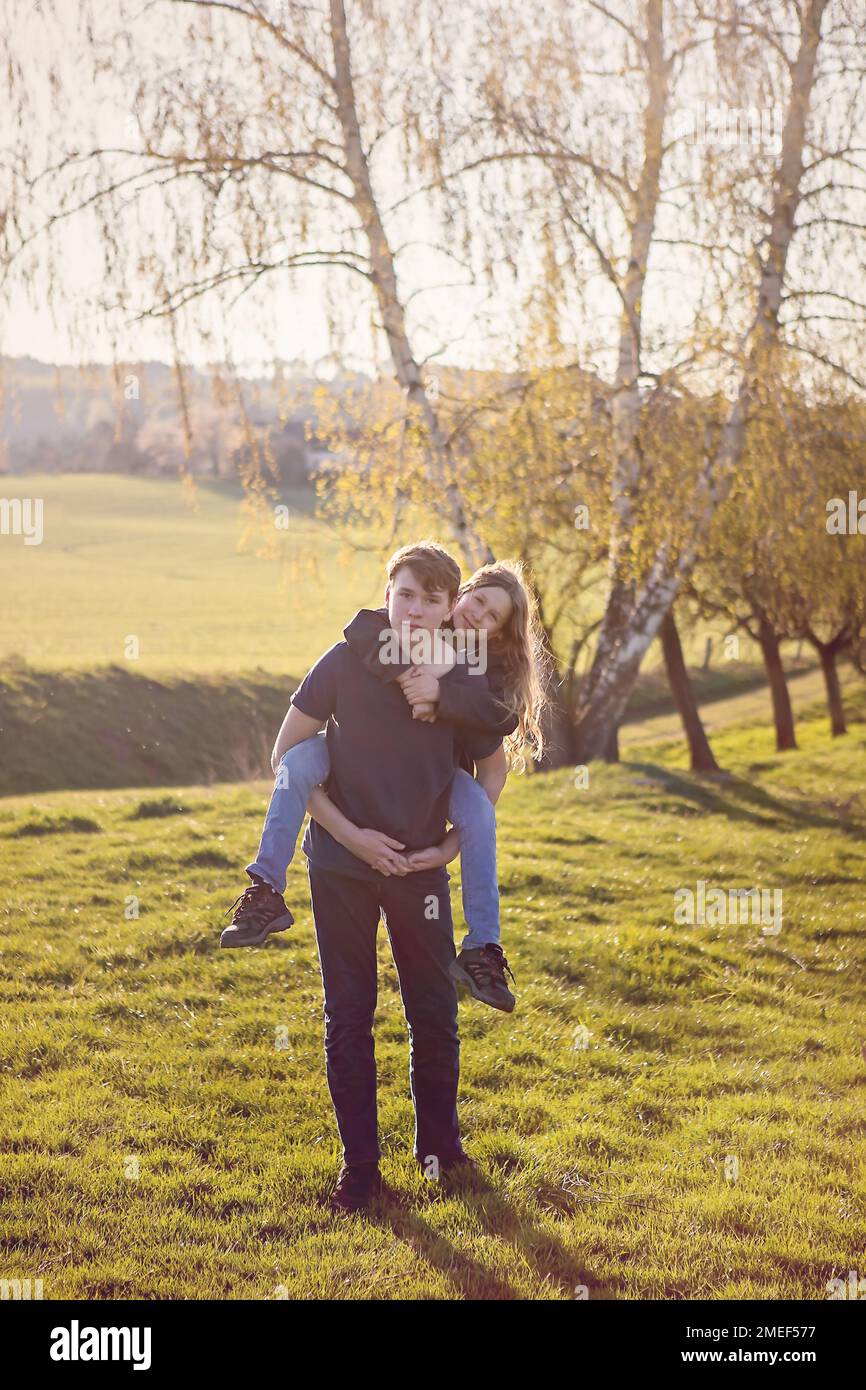 Fratelli e sorelle, divertimento per tutta la famiglia. Ragazzo che tiene la sorella più giovane sulla schiena. Ragazza con lunghi capelli blong, felice, giocare insieme. Foto Stock