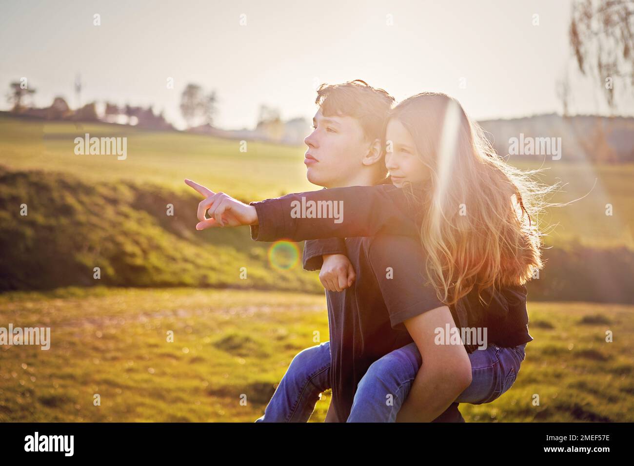 Ragazzo e ragazza, fratello e sorella, fratelli, che interagiscono in una giornata di sole, durante il tramonto nella natura. Splendidi bambini che condividono momenti in famiglia all'aperto Foto Stock