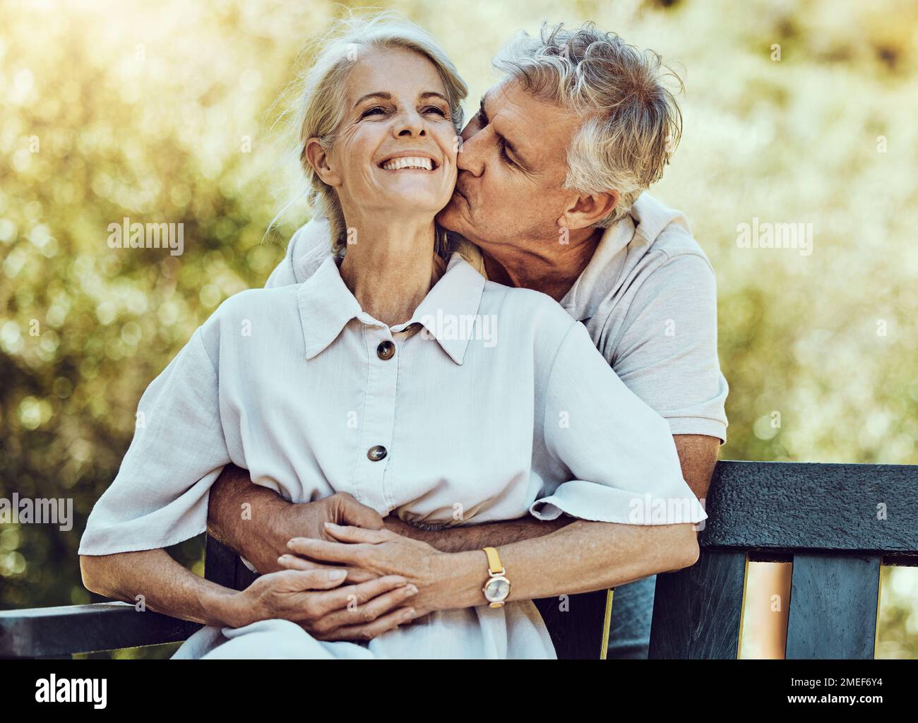 Felice coppia anziana, abbraccio e bacio nel parco con amore, matrimonio e partnership con la pensione insieme all'aria aperta nella natura. Anziani, partner di vita con cura Foto Stock