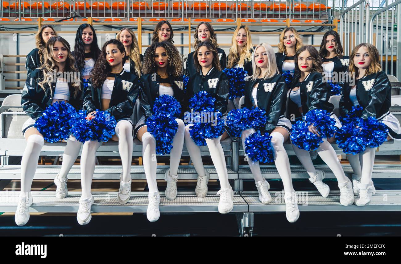 Cheerleaders femminile seduta in due file. Indossano felpe con cappuccio da baseball nere. Foto di alta qualità Foto Stock