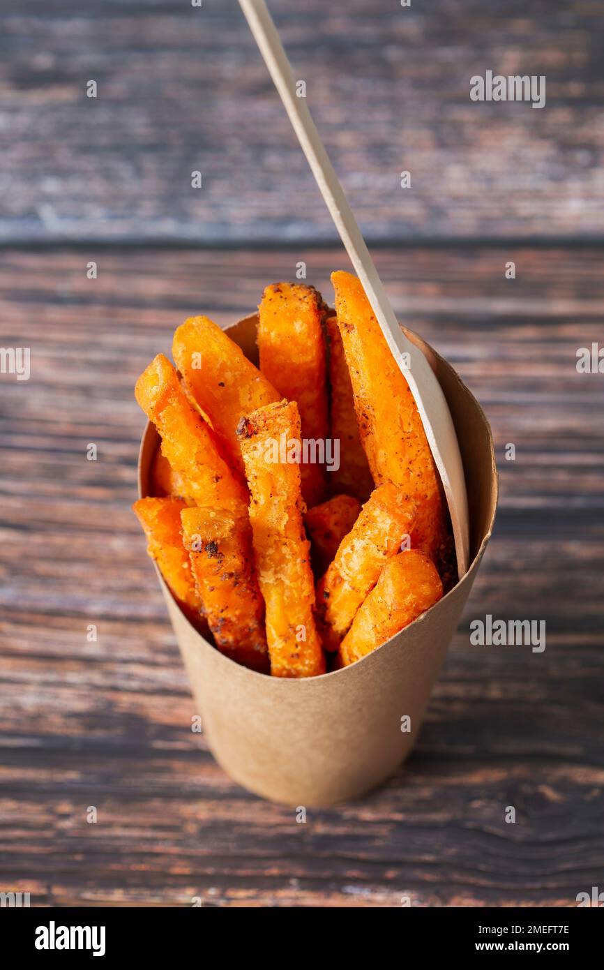 Patata dolce patata in un contenitore di carta da asporto con forchetta di legno. Riciclaggio usa e getta imballaggio sostenibile privo di plastica da asporto Foto Stock