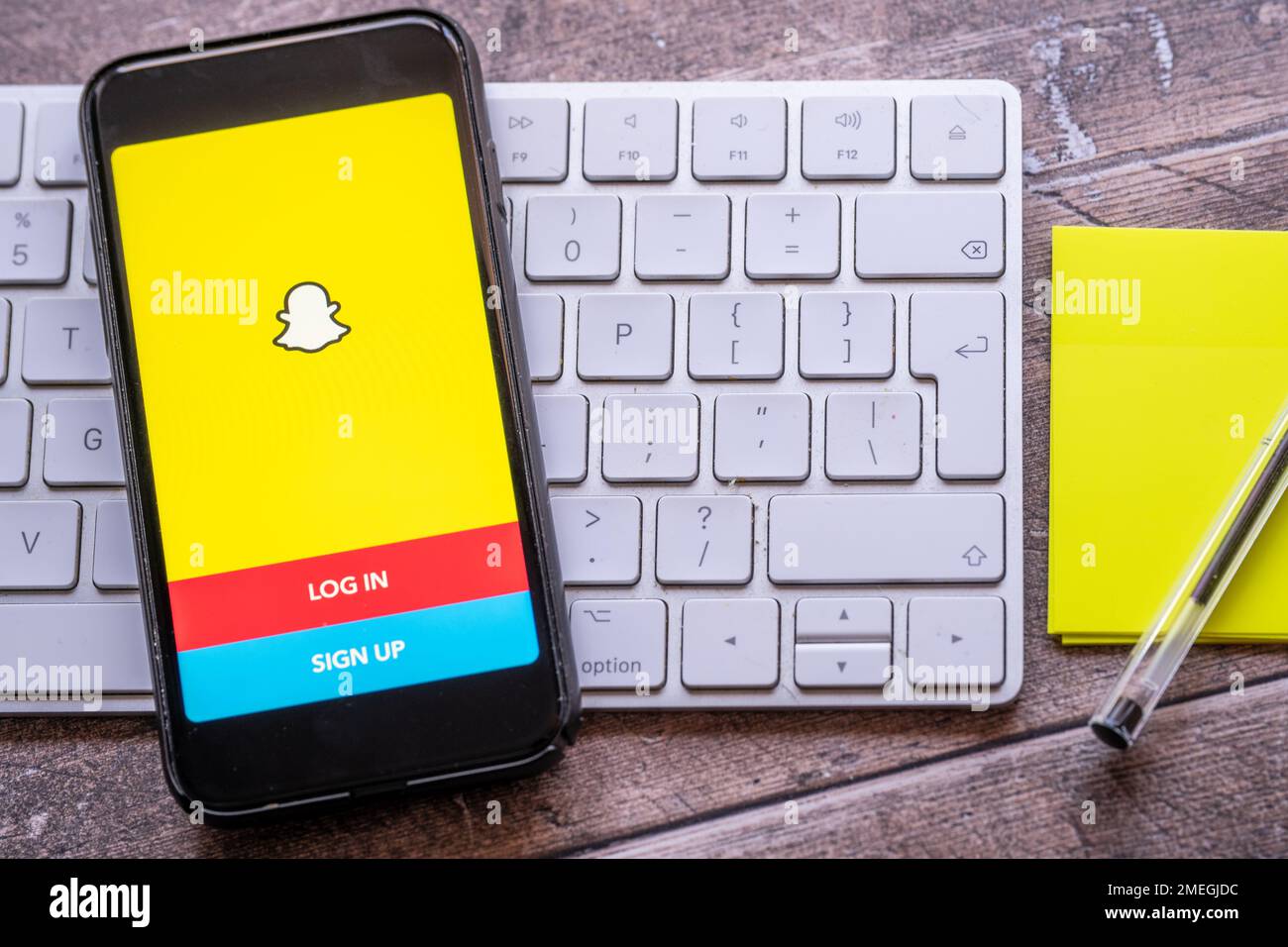 cardiff Mid glamourgan Wales UK Gennaio 24 2023 apertura dell'app di chat SNAP su uno smartphone con tastiera Apple computer e tastiera di scrittura su un de di legno Foto Stock