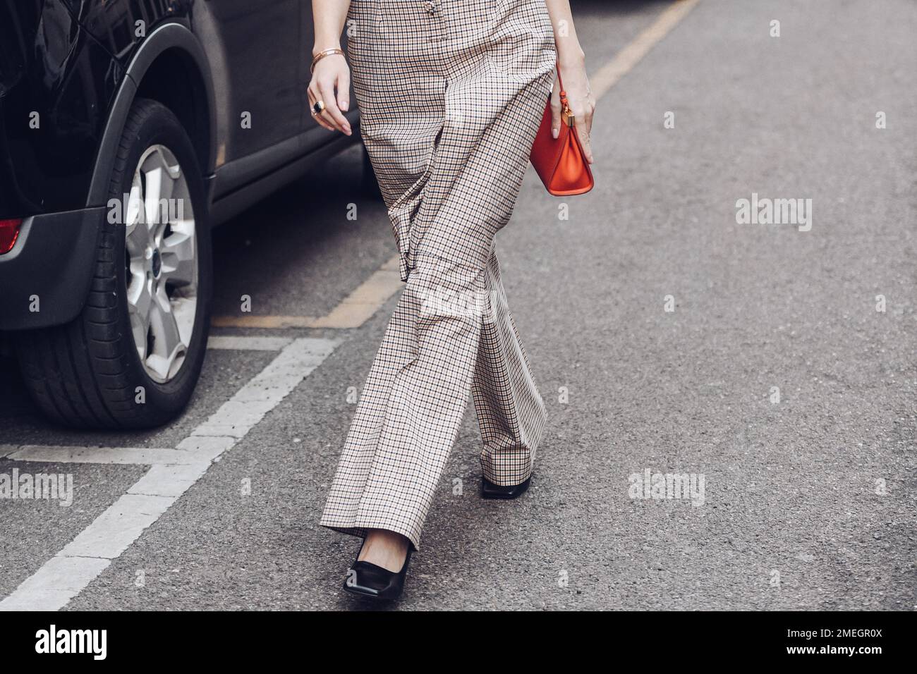 Milano, Italia - 25 febbraio 2022: Donna in abito a scacchi con giubbotto lungo con portamonete piccolo e luminoso. Foto Stock