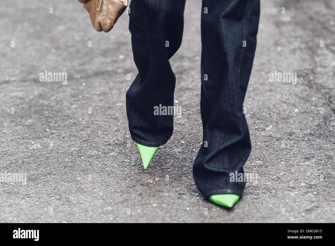 Milano, Italia - 24 febbraio 2022: Donna che indossa lunghi jeans scuri con tacco alto verde chiaro e giacca ornamentale. Foto Stock