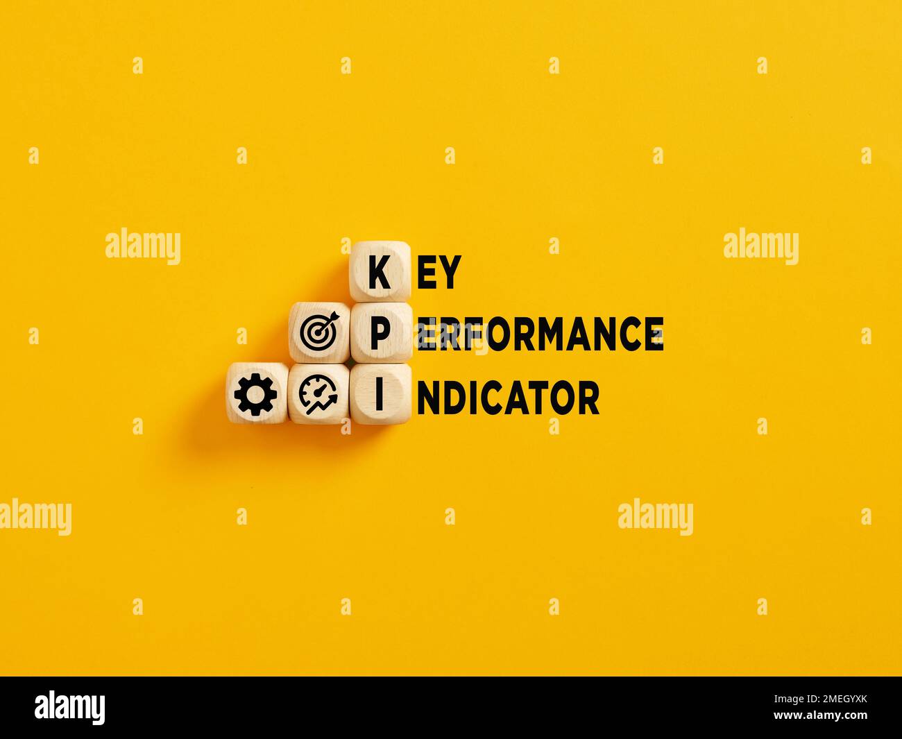 L'acronimo KPI e il testo Key Performance Indicator su cubi di legno su sfondo giallo. Foto Stock