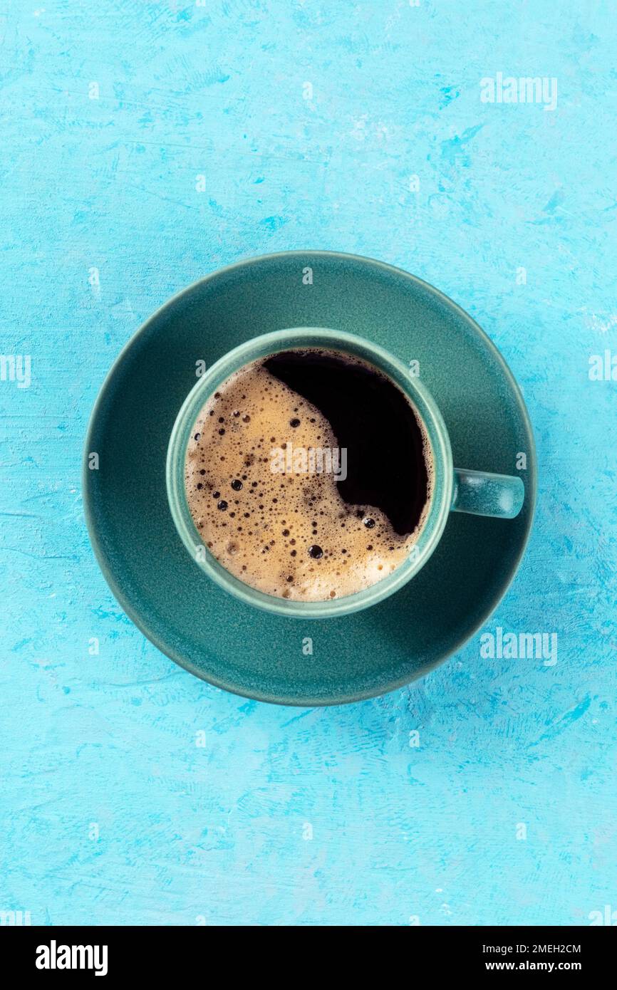 Tazza da caffè, shot superiore su sfondo blu, bevanda espresso su un tavolo turchese, un piatto con spazio per le copie Foto Stock