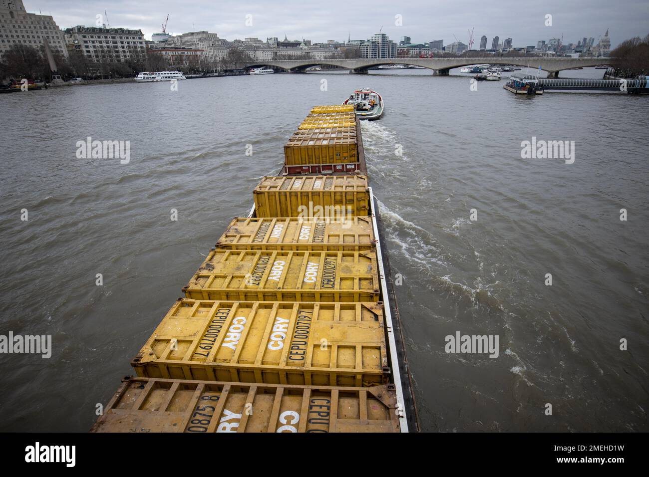 Il carico viene manovrato lungo il Tamigi da una barca Tug in un pomeriggio d'inverno, Londra, Inghilterra, Regno Unito Foto Stock