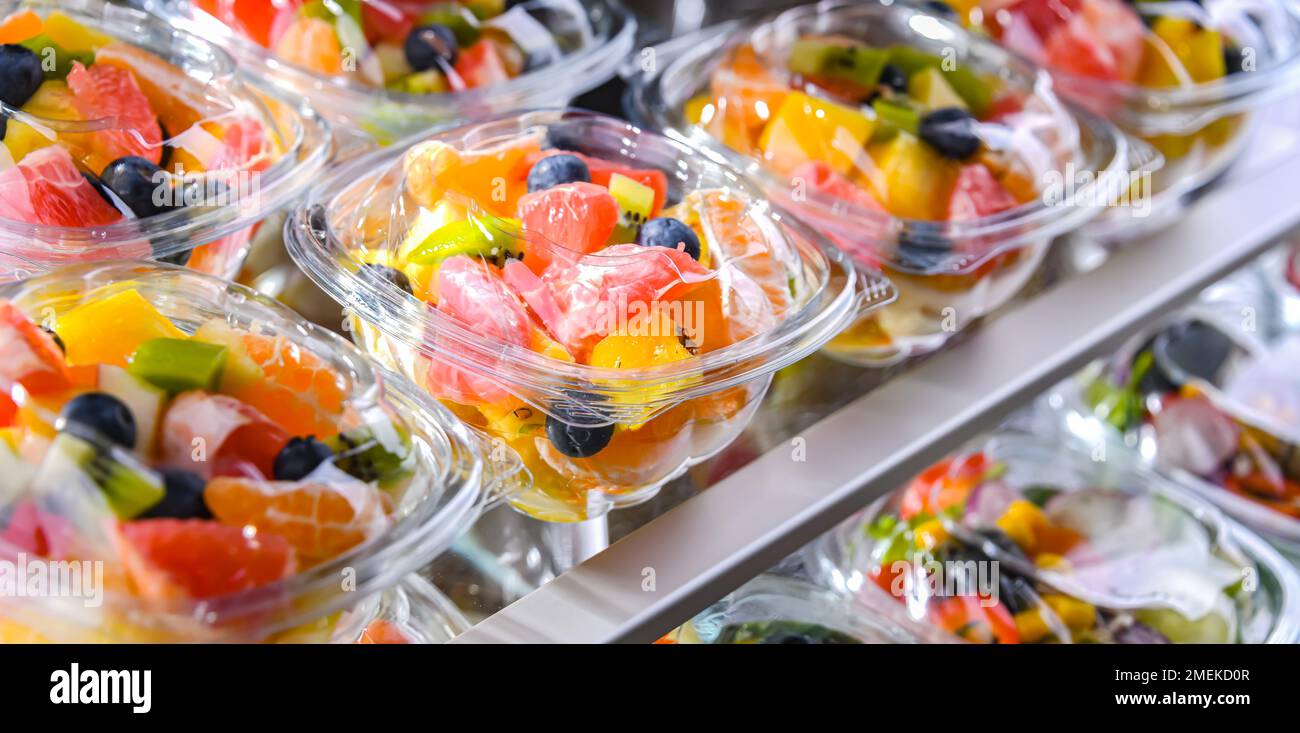 Scatole di plastica con macedonie di frutta preconfezionate, messe in vendita in un frigorifero commerciale Foto Stock