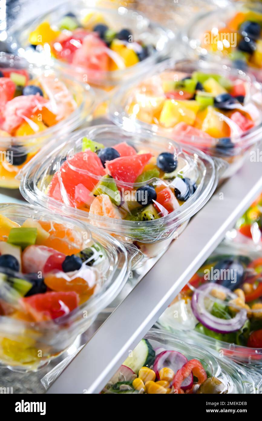 Scatole di plastica con macedonie di frutta preconfezionate, messe in vendita in un frigorifero commerciale Foto Stock