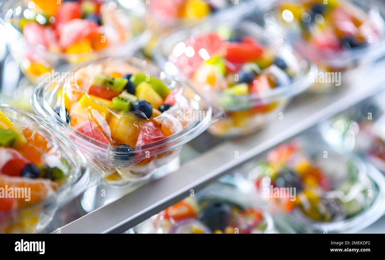 Scatole di plastica con macedonie di frutta preconfezionate, messe in vendita in un frigorifero commerciale Foto Stock