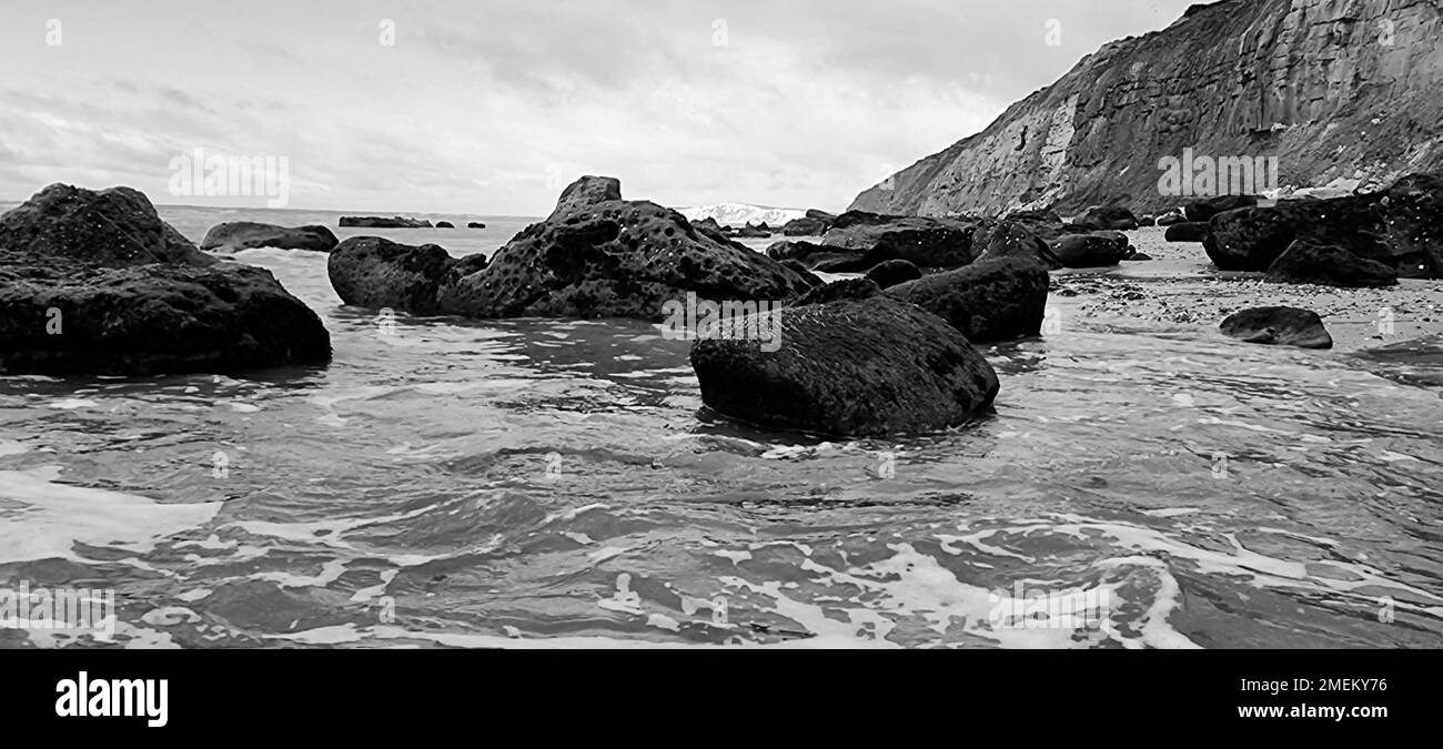 Un colpo in scala di grigi di rocce sulla spiaggia di Brook isola di wight e scogliera rocciosa Foto Stock