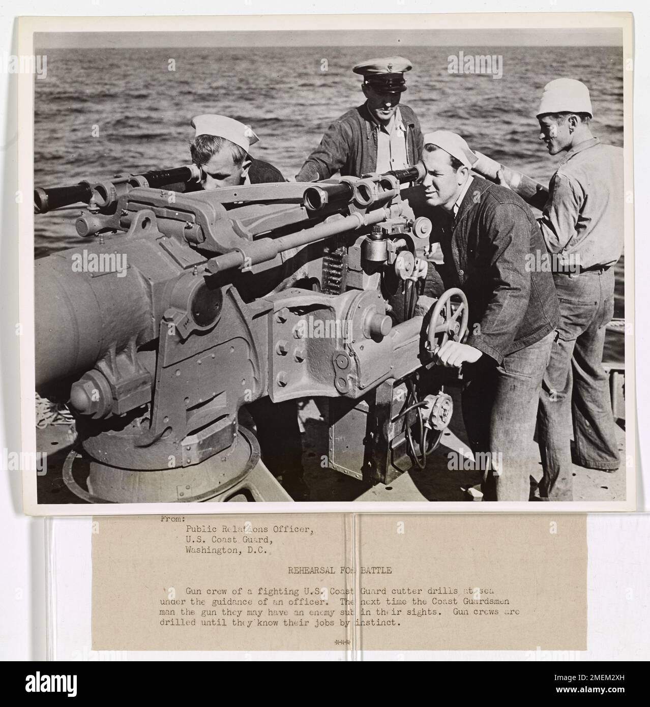 Le guardie costiere a bordo di un cutter della Guardia Costiera degli Stati Uniti conducono un'esercitazione di fuoco in mare sotto la guida di un ufficiale, preparandosi per le situazioni di combattimento e garantendo la preparazione per gli impegni futuri. Foto Stock