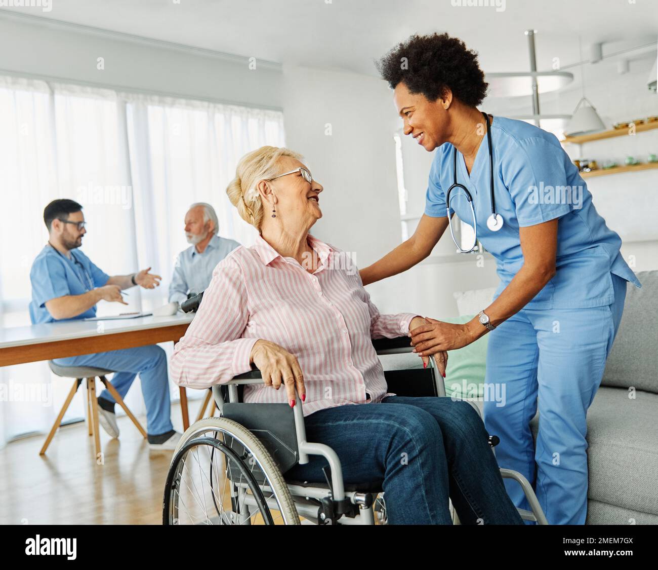 infermiere medico di assistenza senior assistente assistenza sedia a rotelle pensione casa infermieristica anziana donna disabili Foto Stock