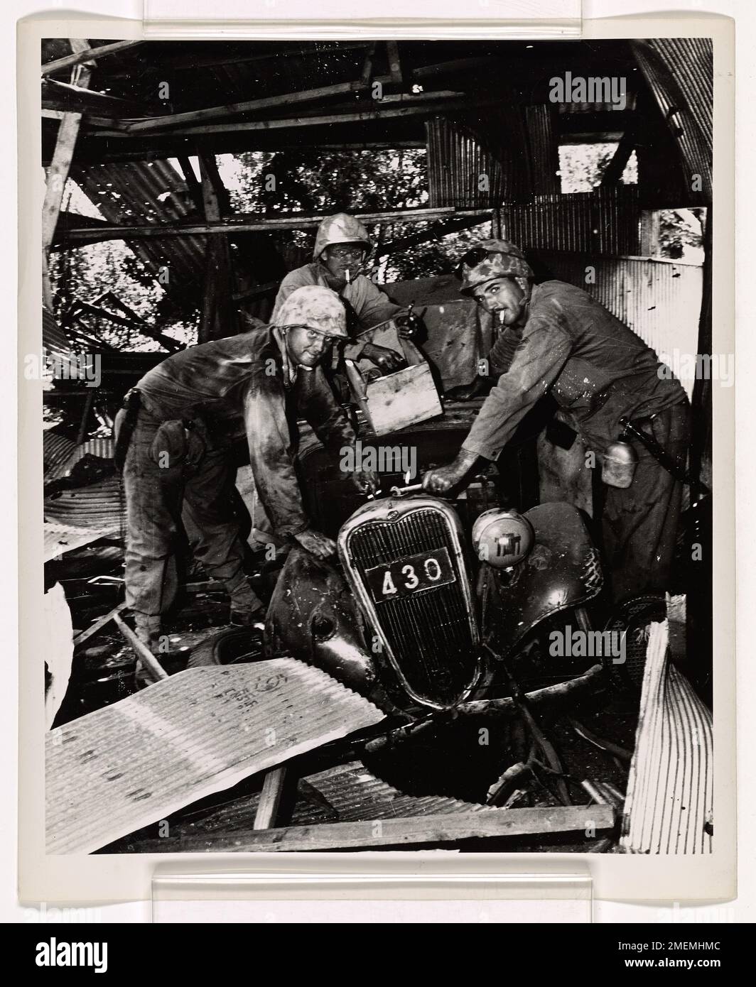 Tre Marine, ricoperti di sporcizia, scoprono un veicolo giapponese, una "Lizzie di stagno", proveniente da un garage distrutto a Charon-Kanoa, Saipan, dopo che un fotografo di combattimento della Guardia Costiera ha catturato la scena. Foto Stock