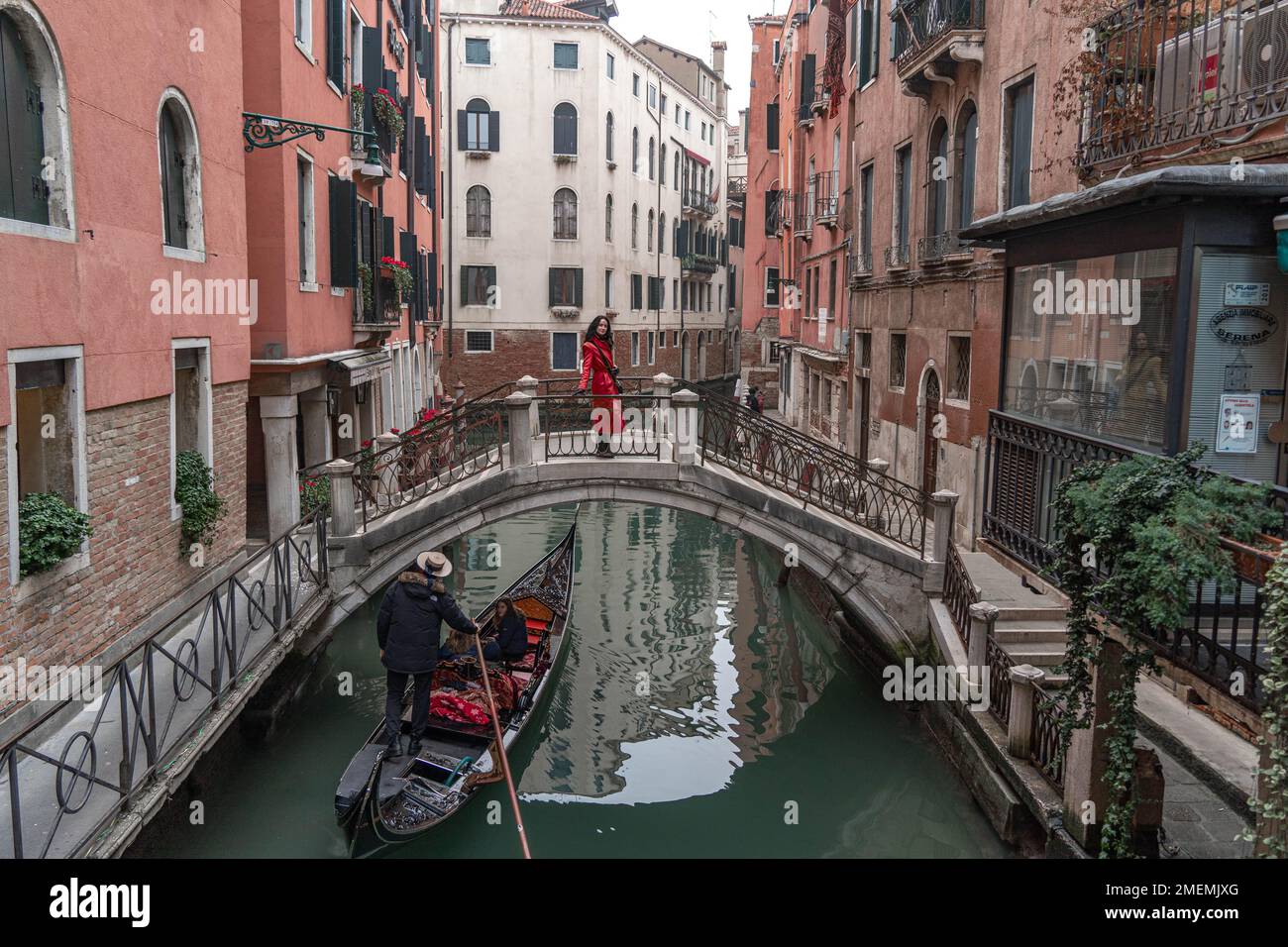 La gondola scorre sotto il ponte nello stretto canale di Venezia, in inverno Foto Stock