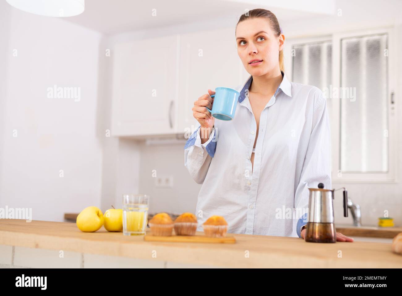 Donna che beve caffè in appartamento Foto Stock