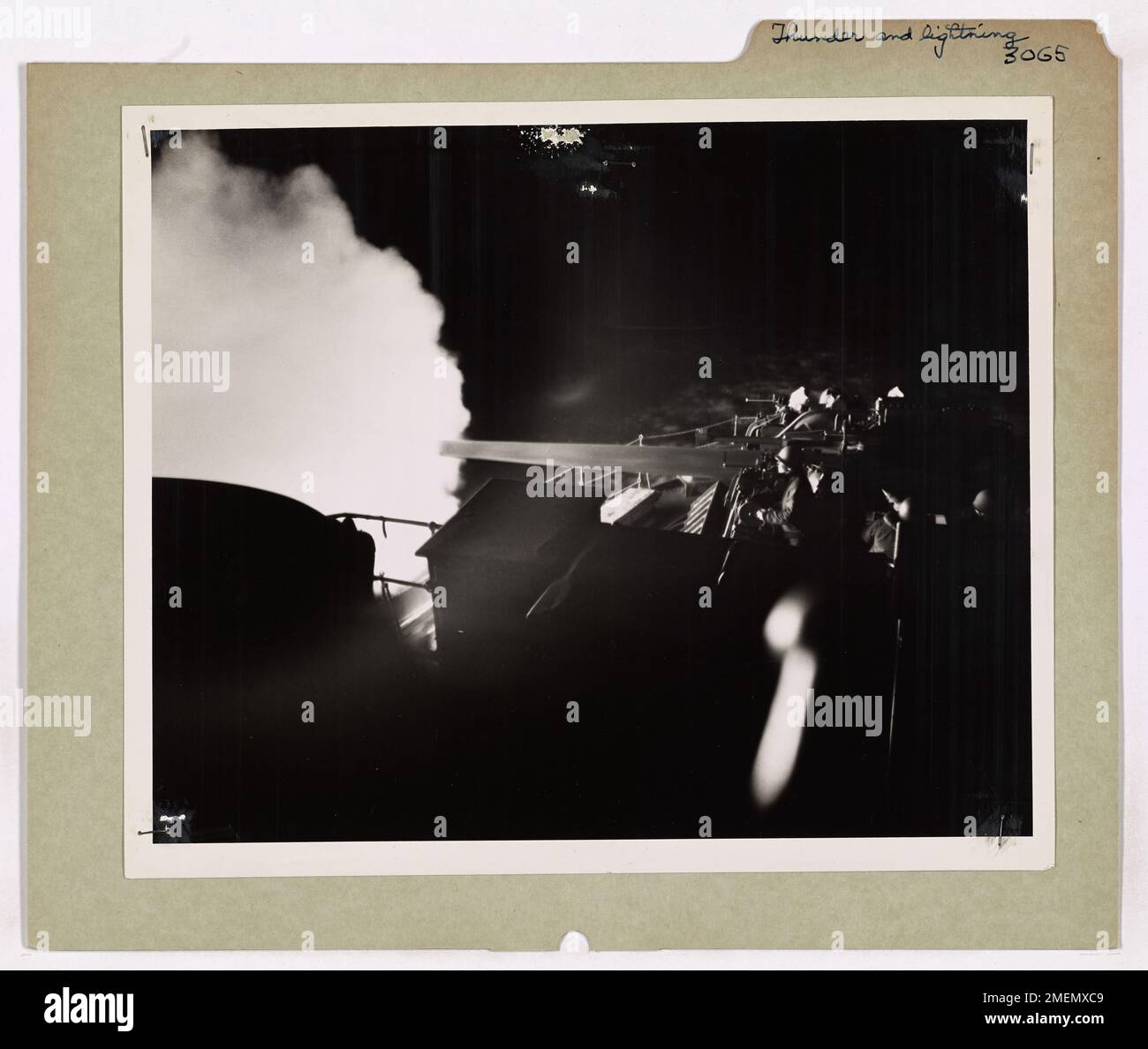 Durante un'esercitazione notturna a bordo di un cutter da combattimento della Guardia Costiera nel Nord Atlantico, un equipaggio di cannoni spara un cannone da 5 pollici. Il flash della pistola illumina la poppa della nave, creando un effetto inquietante e drammatico mentre l'equipaggio pratica la propria preparazione alla battaglia. Foto Stock