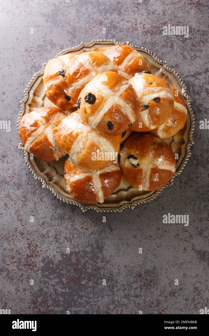 Hot cross buns è un panino dolce speziato di solito fatto con frutta, segnato con una croce sul primo piano sul piatto sul tavolo. Vista verticale dall'alto da Foto Stock