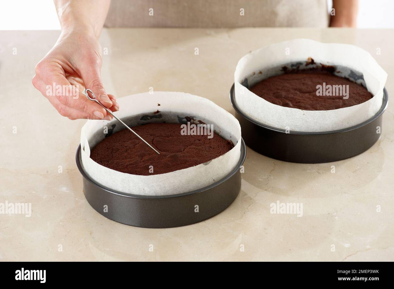 Torta al cioccolato, inserendo uno spiedino per verificare se la torta è fatta Foto Stock