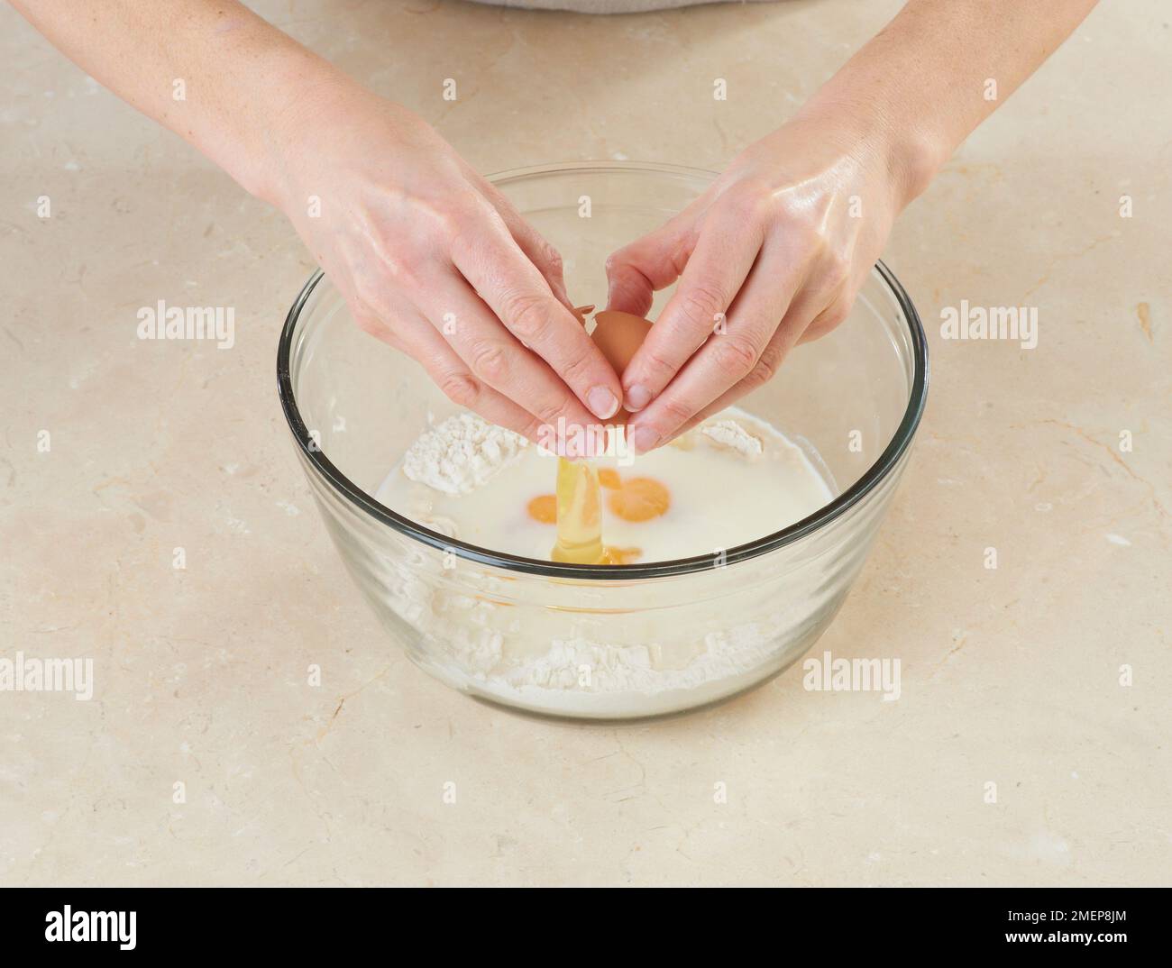 Preparazione di Crepes Suzette, cracking uova in latte e miscela di farina Foto Stock
