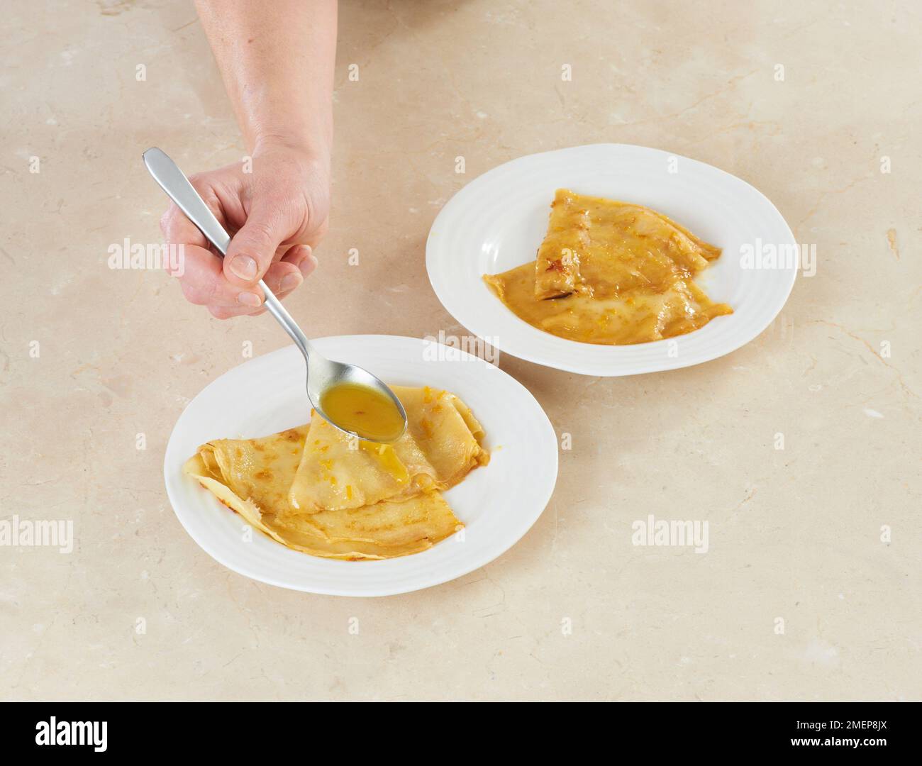 Preparazione della Suzette di Crepes, cucchiaiata di salsa sopra di loro Foto Stock