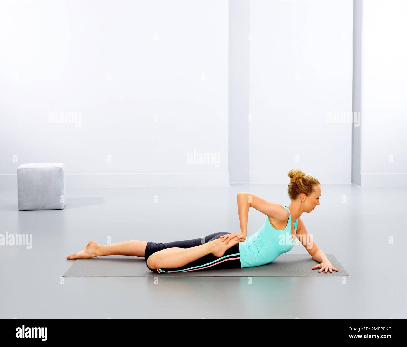 Donna che esegue un esercizio di yoga sul tappetino, vista laterale Foto Stock