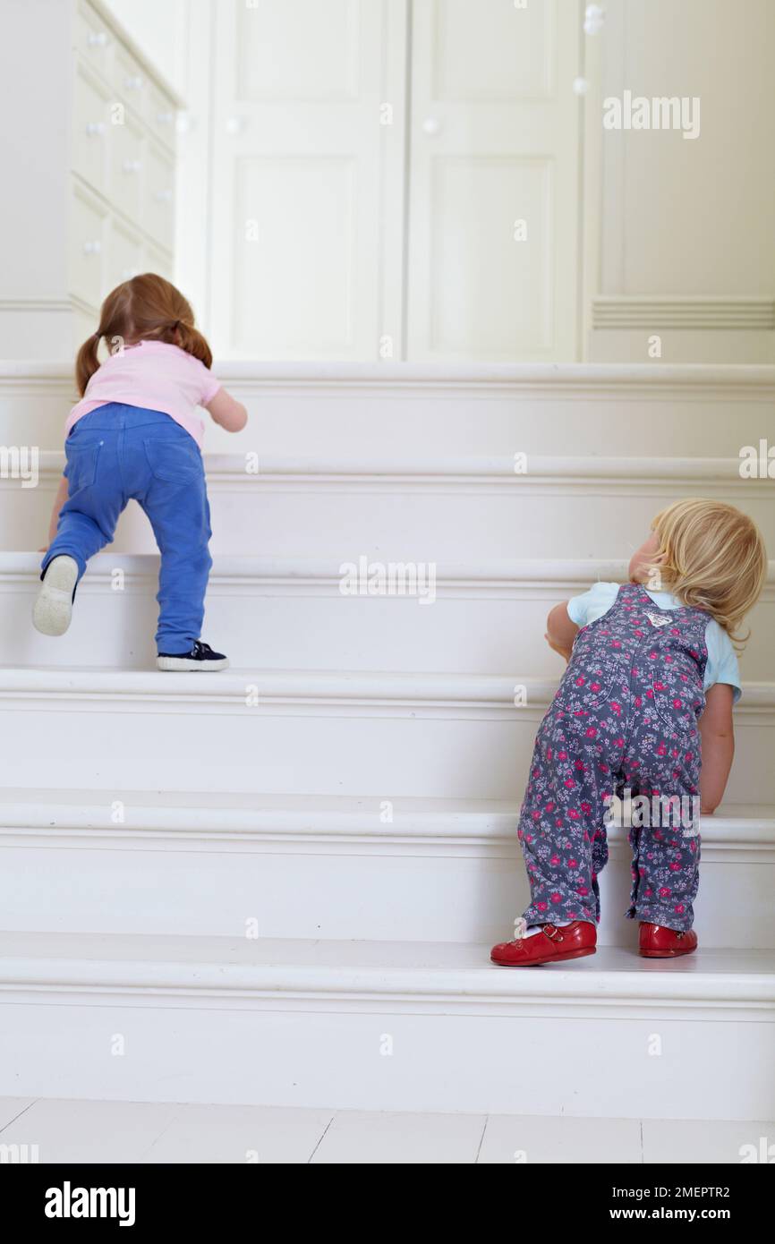 Due ragazze che salgono le scale, 2 anni e 18 mesi Foto Stock