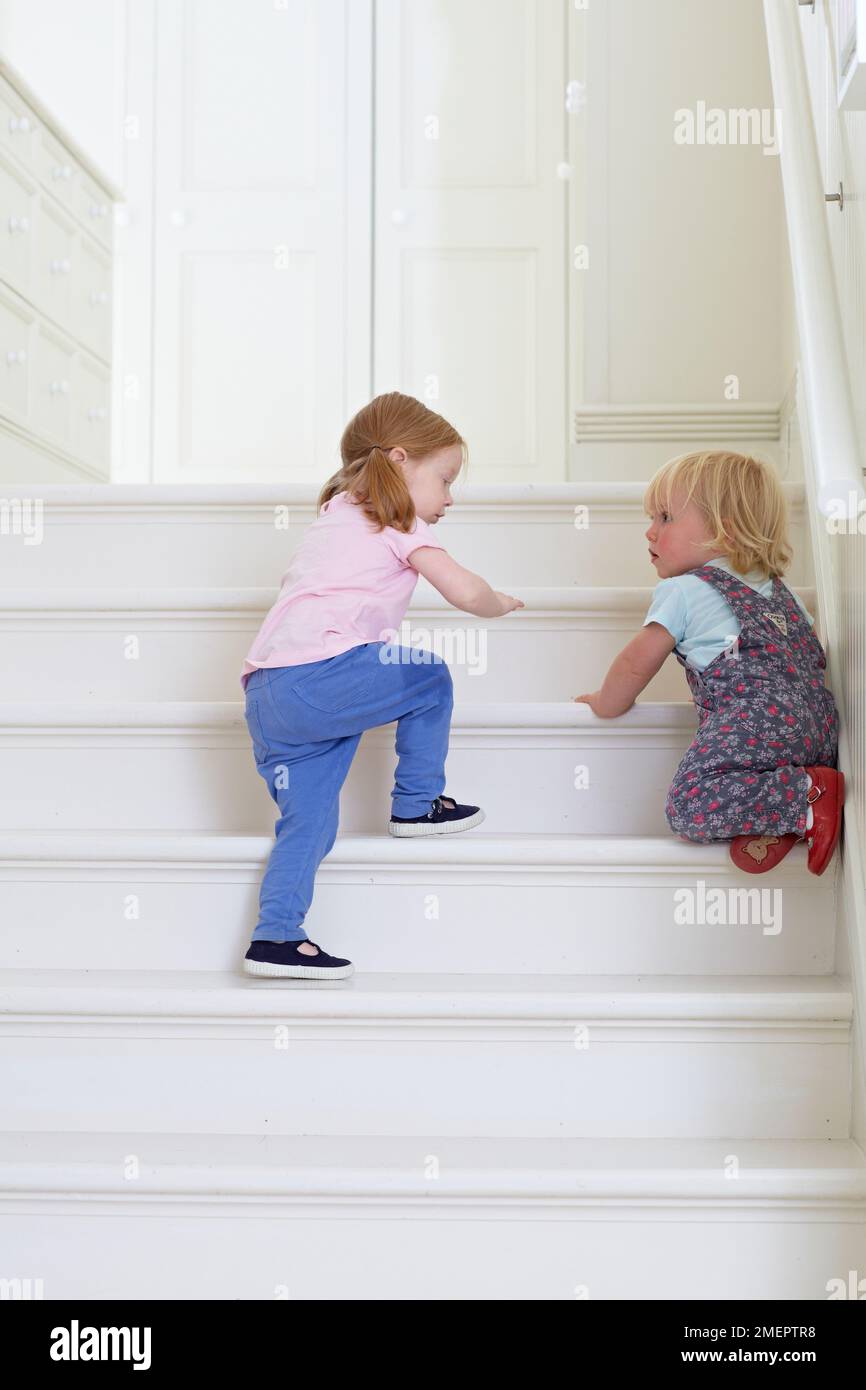 Ragazza giovane che sale le scale con il bambino, 2 anni e 18 mesi Foto Stock