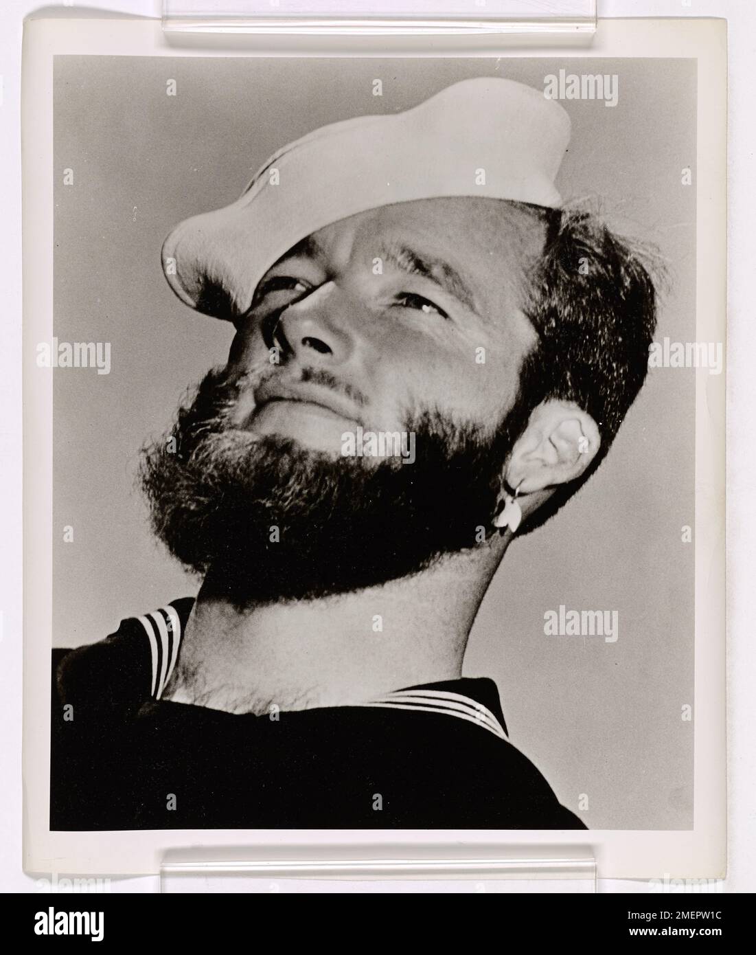 Il guardiano della costa Kent C. Pompella è raffigurato indossando distintivi ornamenti facciali come il mento di un castoro e i denti di squalo, che fanno parte dell'abbigliamento tradizionale degli isolani del Mare del Sud. L'immagine evidenzia gli elementi culturali della regione. Foto Stock