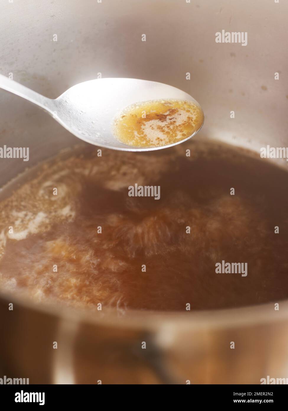 Skimming via la gomma dalla superficie del brodo di carne (cottura della salsa di espagnole) Foto Stock