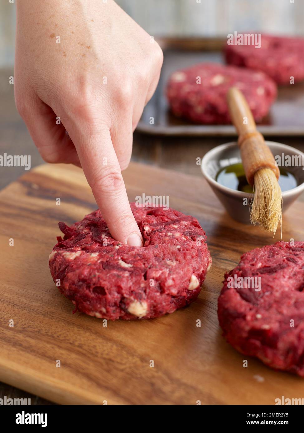 Utilizzando il dito per testare la consistenza della carne di manzo, barbabietole e stilton burger Foto Stock