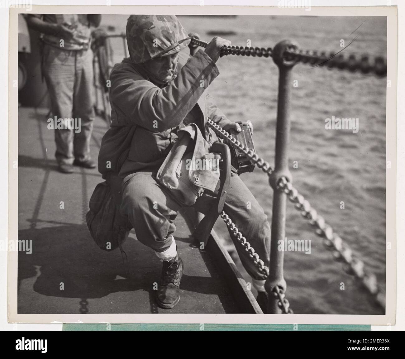 New London Coast Guard Photog 'Covers' Okinawa. Il fotografo di combattimento della Guardia costiera Thomas L. Lonergan di 120 Norwood Ave., New London, Conn., incontra la sua prima opposizione alla ferrovia della nave mentre va oltre il fianco con attrezzature da battaglia complete e telecamere per film d'azione su Okinawa. Coast Guardsman Lonergan, un compagno di fotografi capo, è andato a riva da una nave di invasione con equipaggio della Guardia Costiera. Foto Stock