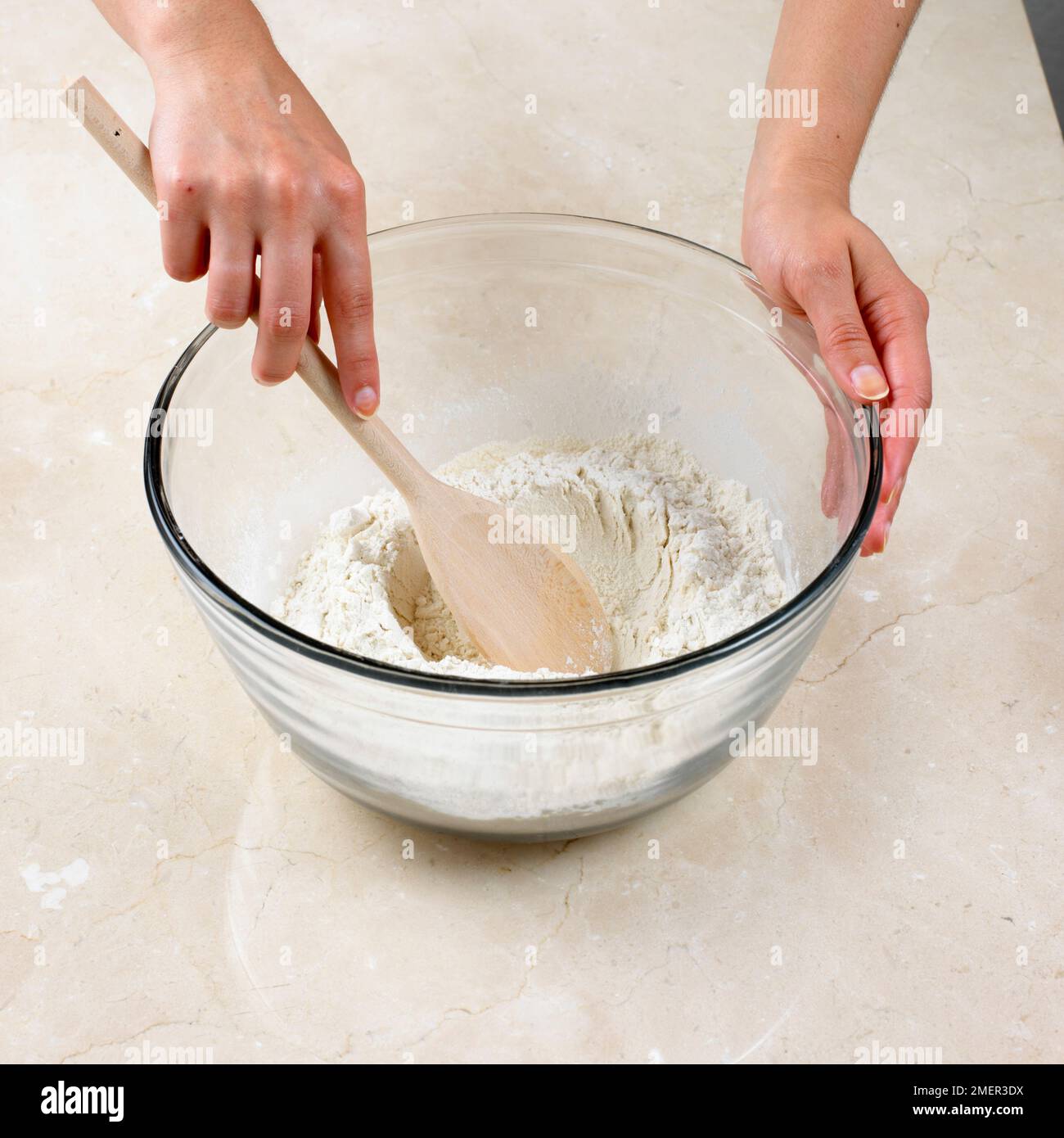 Preparare la pasta di crosta in acqua calda, utilizzando un cucchiaio per ottenere un composto ben al centro della farina Foto Stock
