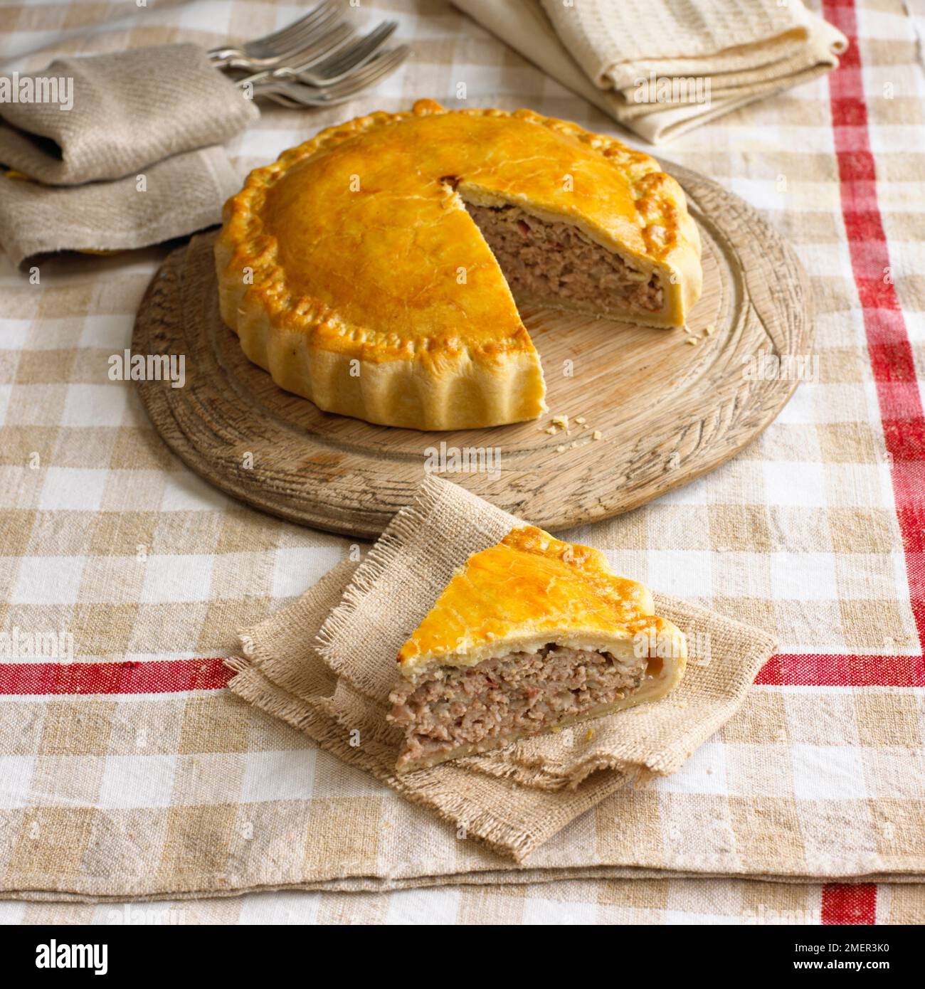 Torta da picnic di maiale e mela con una singola fetta tagliata lontano dal resto Foto Stock