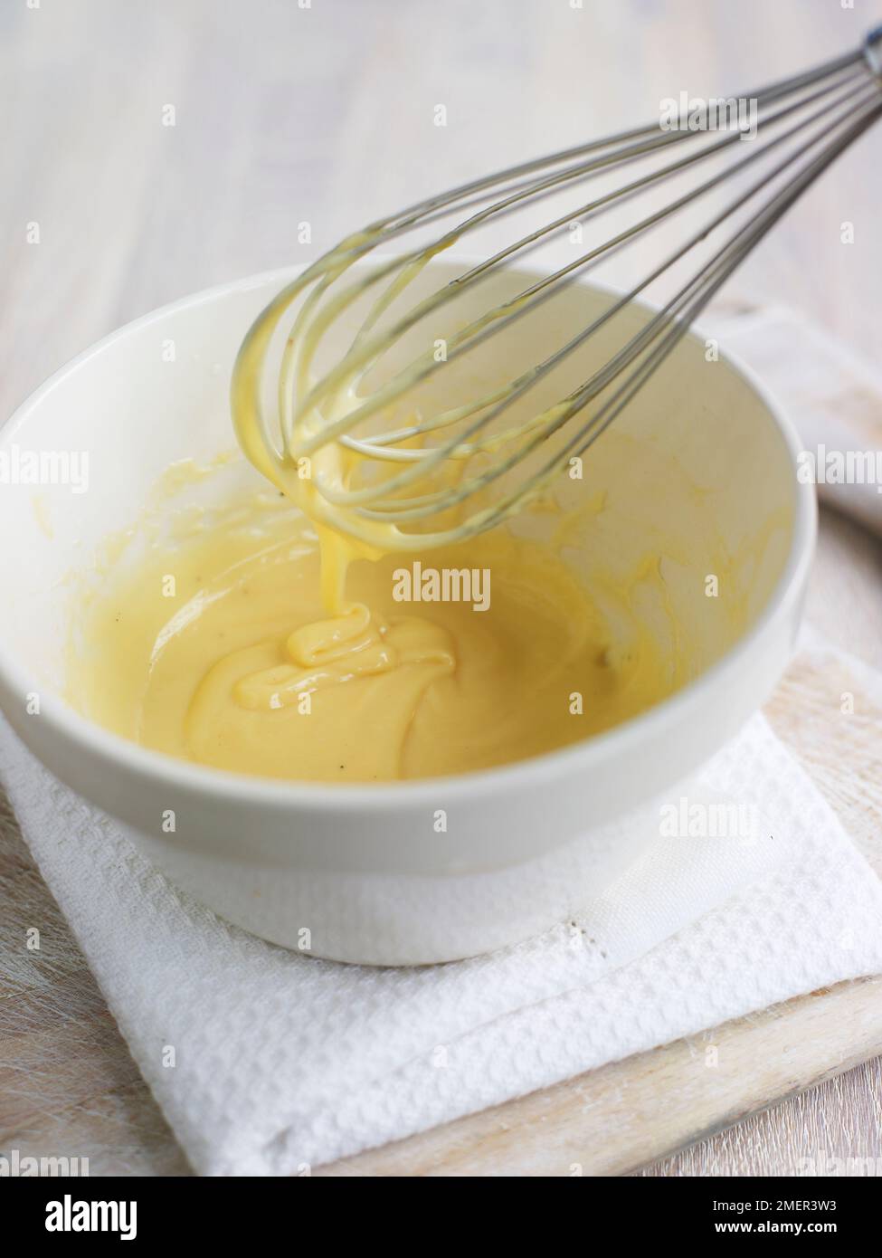 Maionese nel recipiente e gocciolando dalla frusta metallica Foto Stock