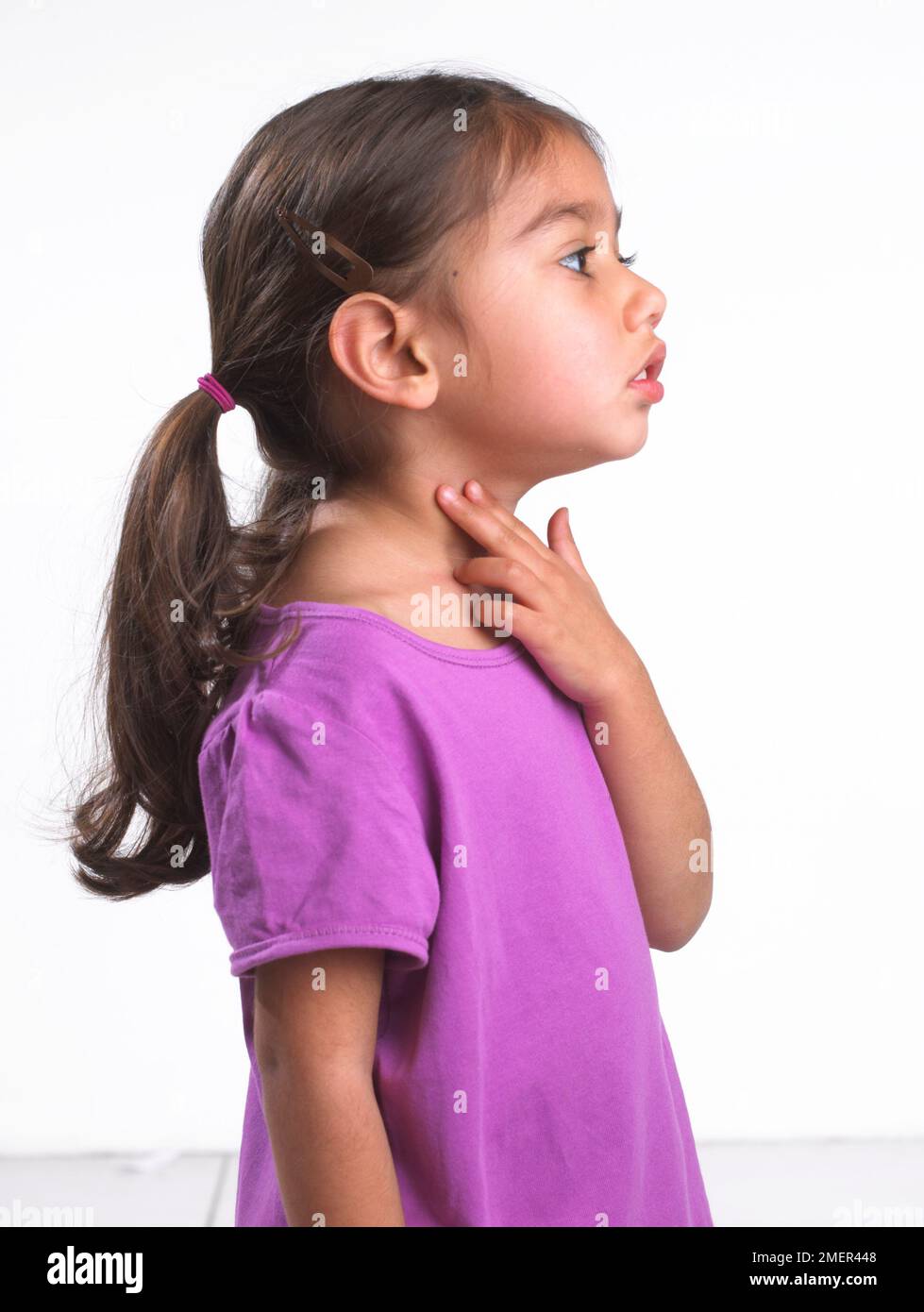 Ragazza che indossa la parte superiore rosa che tocca la gola, vista laterale, 3,5 anni Foto Stock