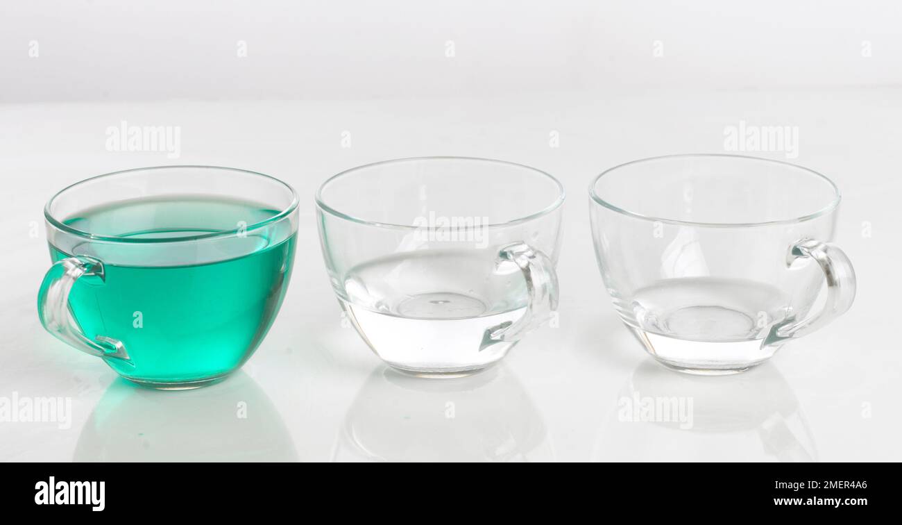 Tre tazze d'acqua, una verde, le altre due limpide Foto Stock