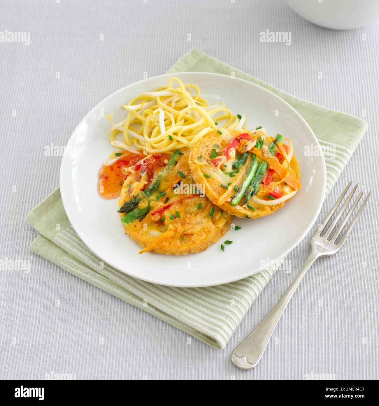 Barbabietole in stile thailandese e frittelle di verdure grattugiate, servite con insalata di noodle e barbabietole e salsa al peperoncino dolce Foto Stock