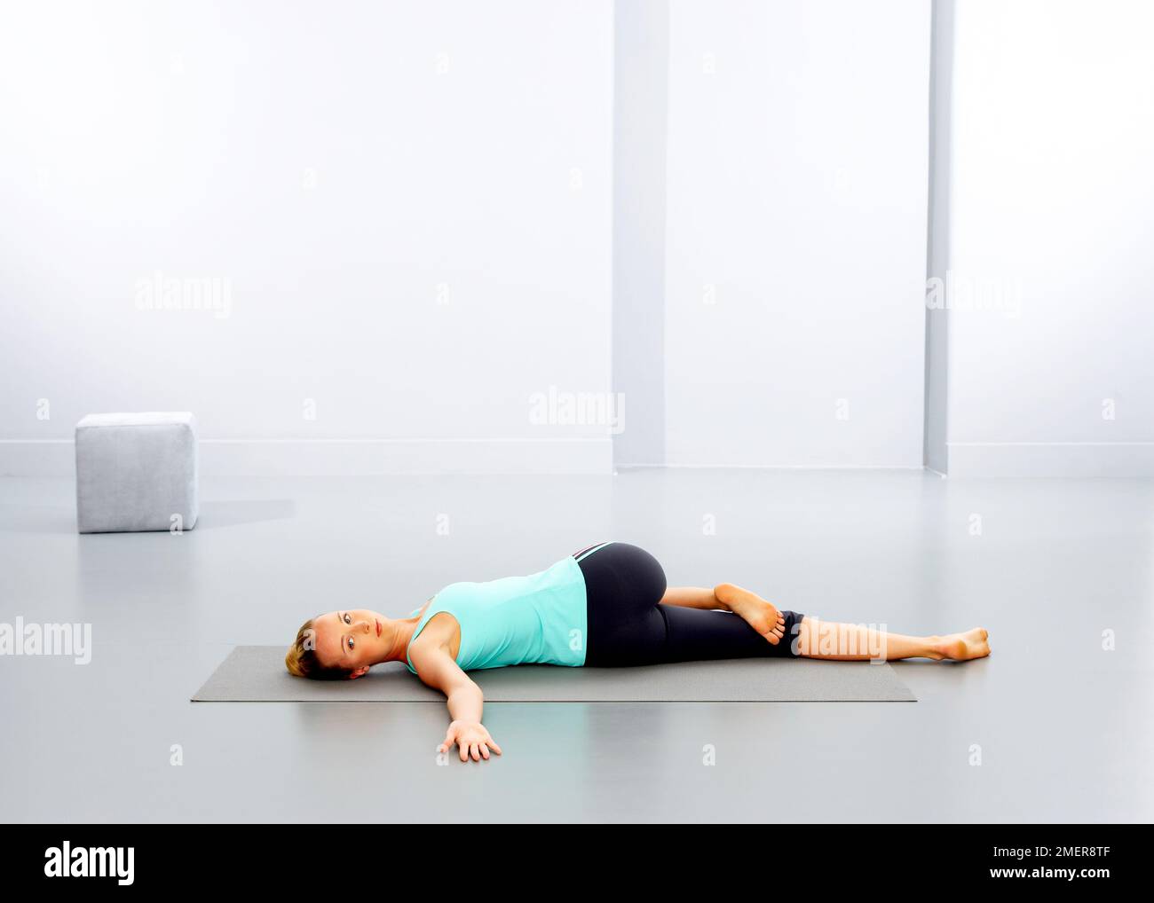 Donna che pratica yoga sul tappeto Foto Stock