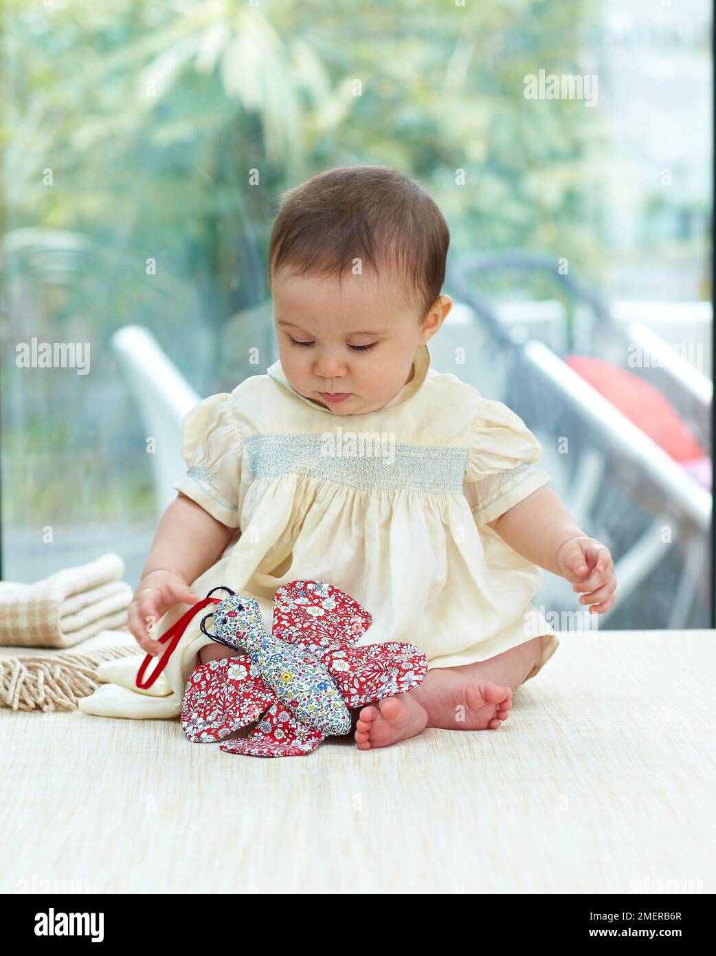 Bambina seduta a giocare con la farfalla giocattolo, 6,5 mesi Foto Stock