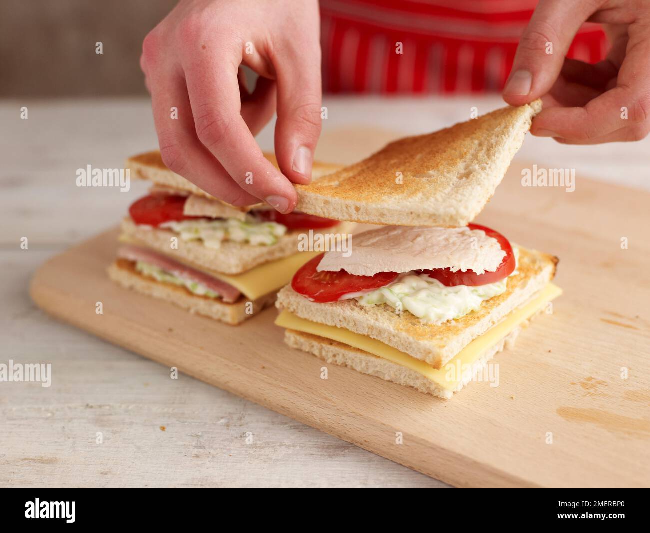 Aggiungere una terza fetta di pane bianco tostato sul panino del club Foto Stock