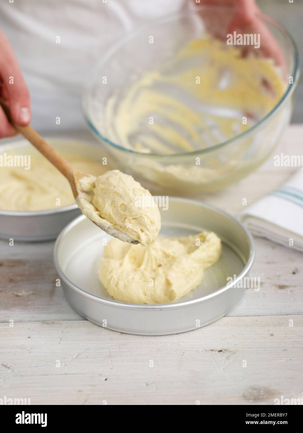 Cucchiaiate il composto di pan di Spagna in tini rotondi da forno Foto Stock