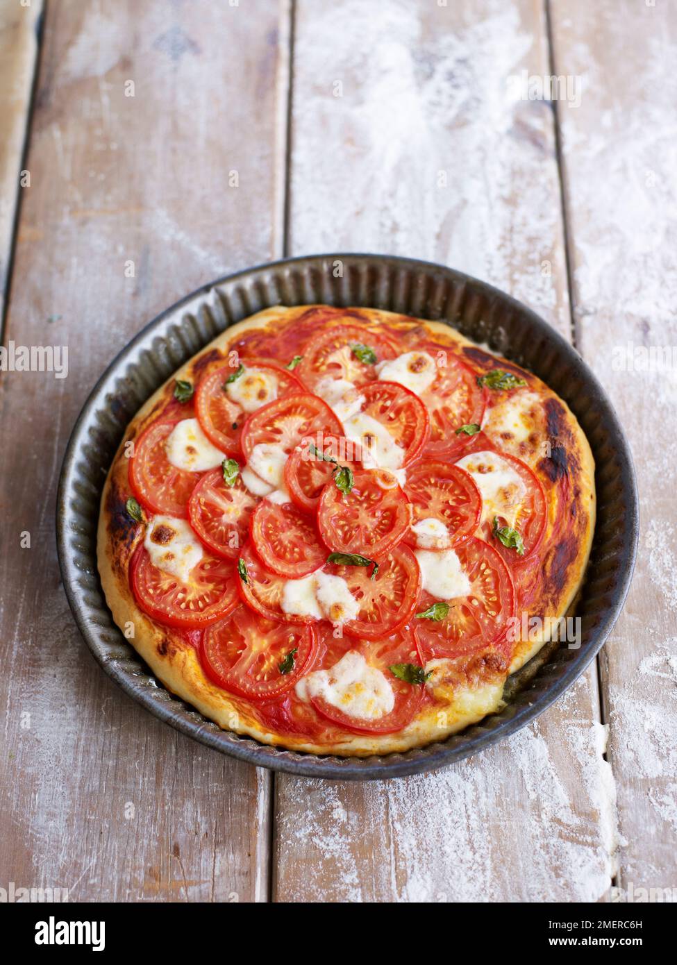 Pizza sormontata con mozzarella e pomodori freschi, foglie di basilico, cotta Foto Stock