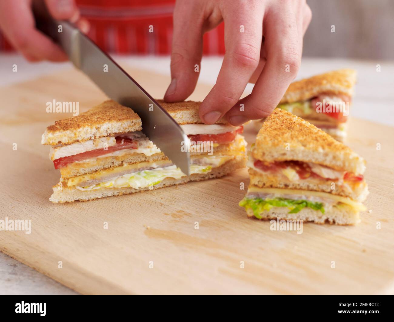 Preparare un panino a tre piani, composto da toast, prosciutto, formaggio e lattuga maionese Foto Stock