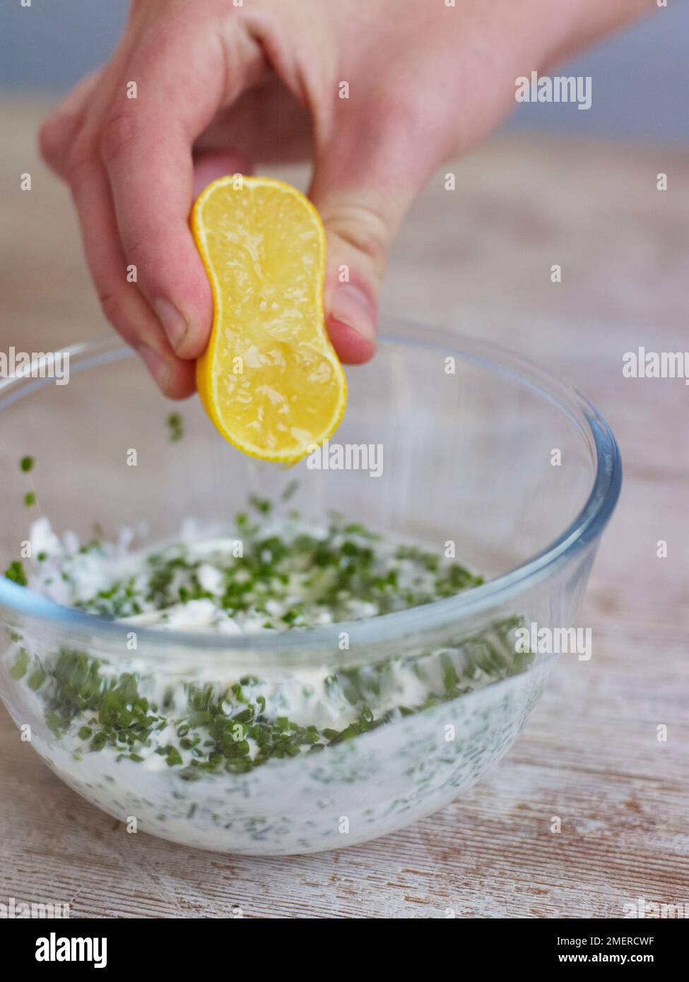 Aggiungere il succo di limone alla panna acida, l'erba cipollina in un recipiente Foto Stock