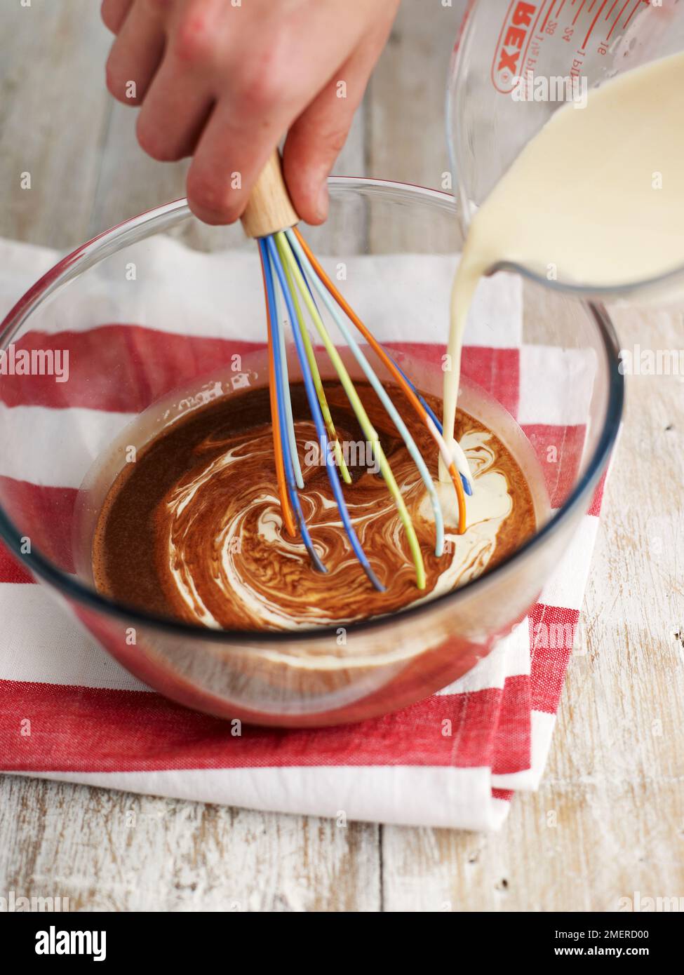 Versare il latte sul composto al cioccolato e frullare, creando un dessert al cioccolato Foto Stock