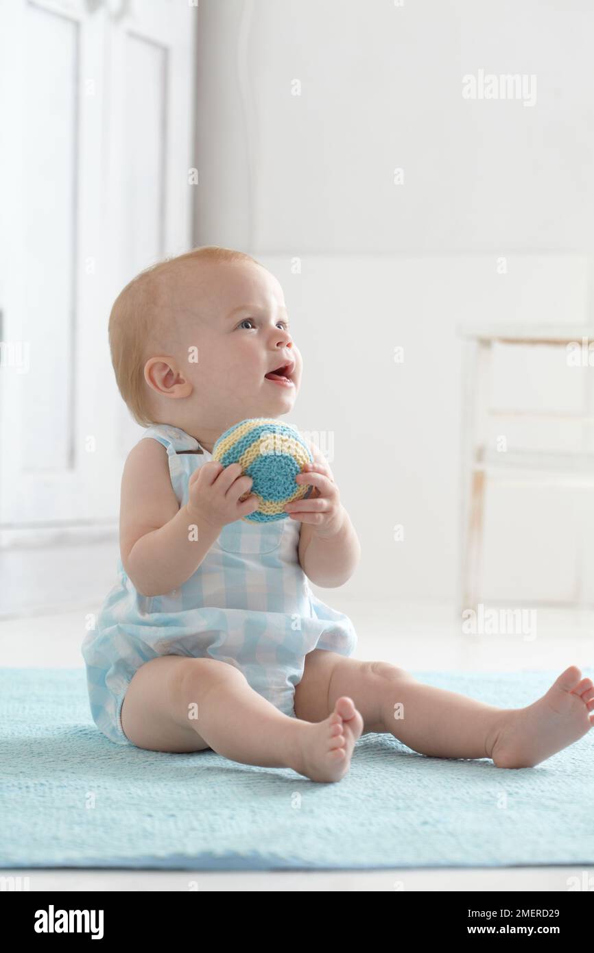 Bambina, con palla giocattolo morbida a maglia, 9 mesi Foto Stock