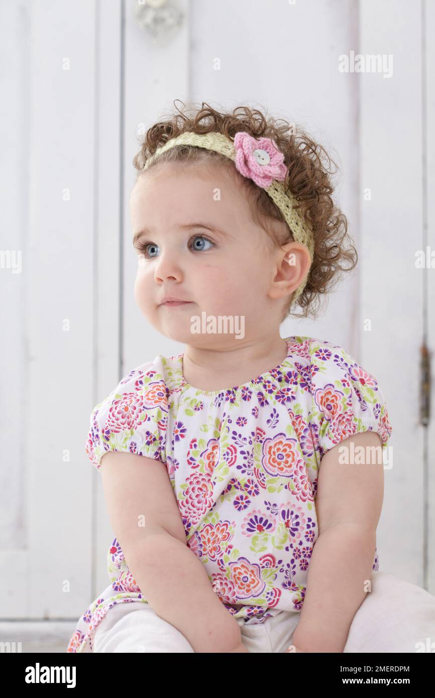 Bambina seduta con fascia in maglia, 14 mesi Foto Stock