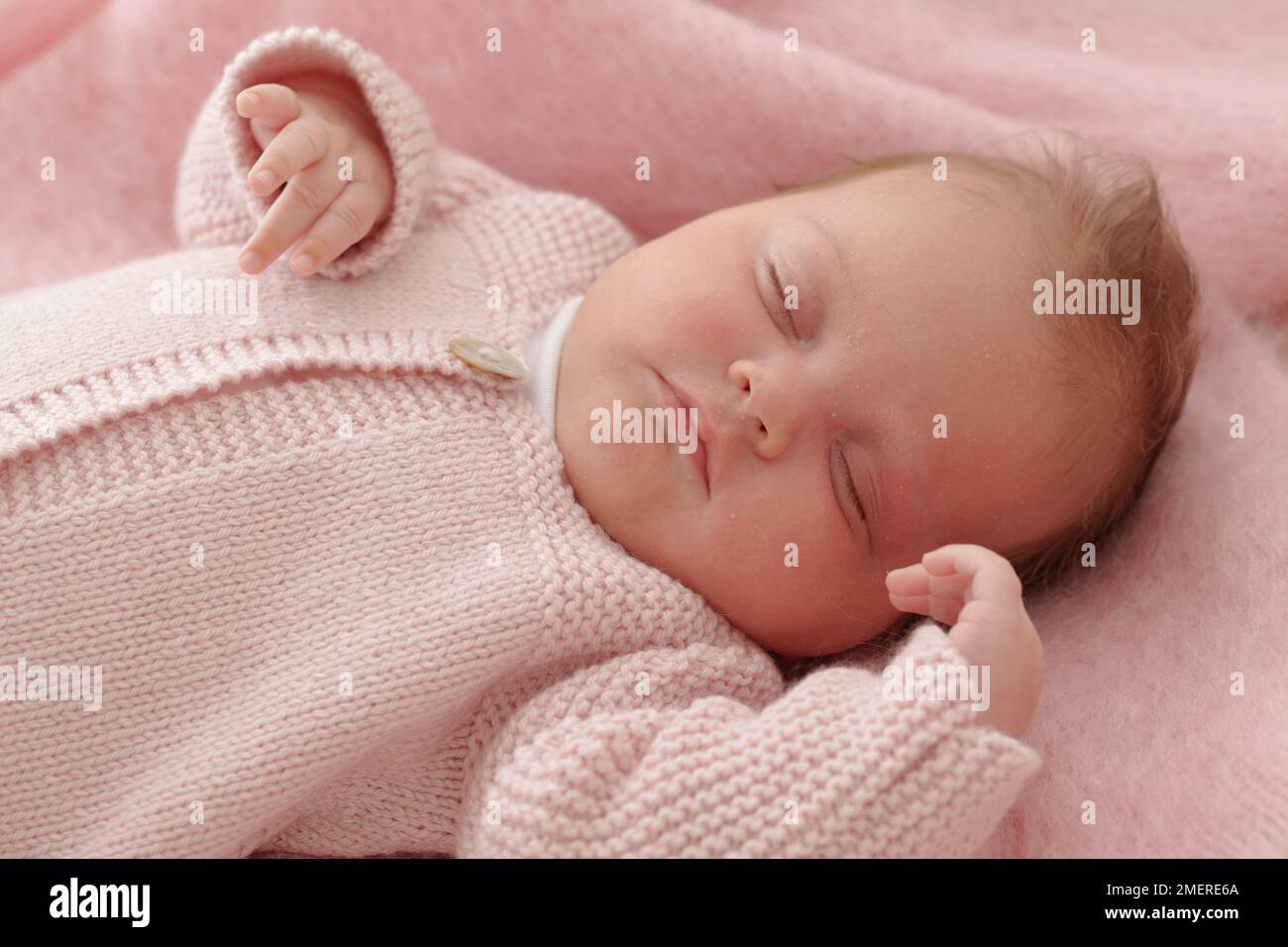 Bambina sdraiata con cardigan a maglia rosa, 6 settimane Foto Stock